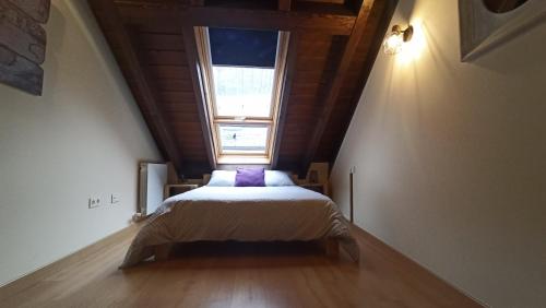 a bedroom with a bed in a attic with a window at El Cielo de Escarrilla in Escarrilla