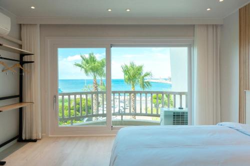a bedroom with a bed and a view of the ocean at Ocean Palade Hotel in Jeju
