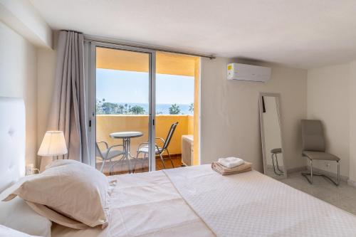 um quarto com uma cama e vista para uma varanda em Beachfront Puerto Cabopino em Marbella
