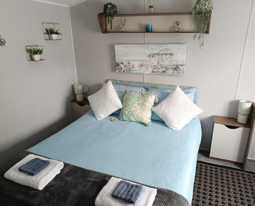 Haven Rockley Park, Lytchett Bay View, Private Holiday Home - Caravan في Lytchett Minster: غرفة نوم بسرير ازرق مع وسادتين
