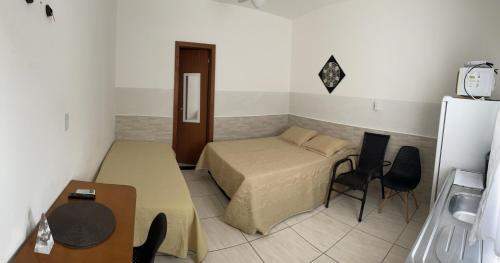 um quarto com uma cama, uma mesa e um frigorífico em TERRAÇO DA BARRA em Florianópolis