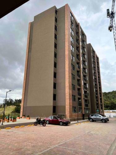 a large building with cars parked in front of it at Nuevo Apartamento frente al Centro Comercial VIVA in Tunja