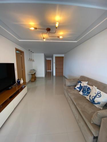 a living room with a couch and a flat screen tv at Apto NOVO BEIRA MAR Praia do Morro vista mar e montanha com 120m 3 qtos Ed Elegance limitado a 8 hóspedes independente da idade in Guarapari