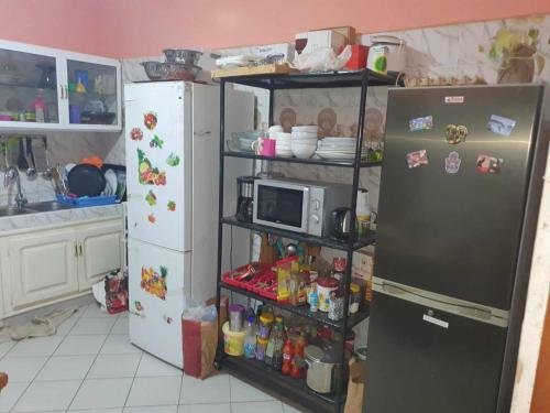 a kitchen with a refrigerator and a microwave at SALY KEUR EMMA in Malikounda Sas