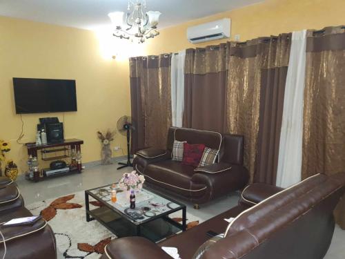 sala de estar con muebles de cuero y TV en SALY KEUR EMMA, en Malikounda Sas