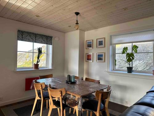 a dining room with a table and chairs and two windows at Nuuk Villa Hostel in Nuuk