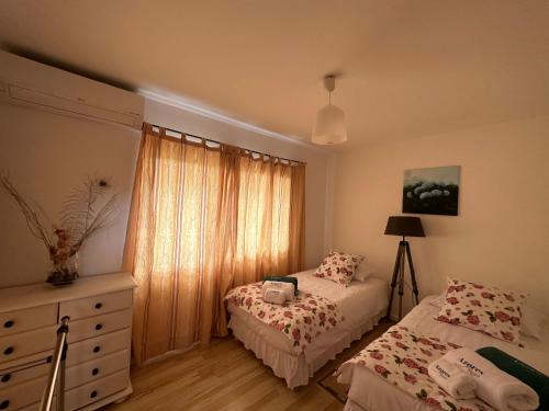 a bedroom with two beds and a dresser and a window at Casa das Hortências by Azoresrent in Farroupo