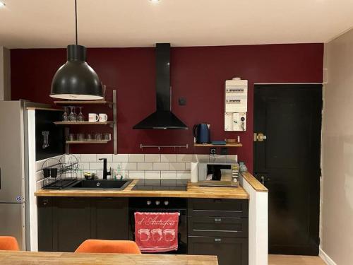 cocina con paredes rojas y encimera en APPARTEMENT CHEZ TRICIA, en Thorigny-sur-Marne