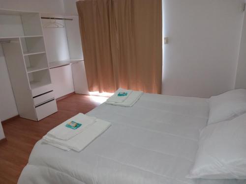 a bedroom with two white beds with towels on them at Rukan in Comodoro Rivadavia