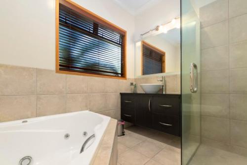 Lake TaraweraにあるRiverstone Lake Taraweraの浴槽、洗面台、鏡のあるバスルーム