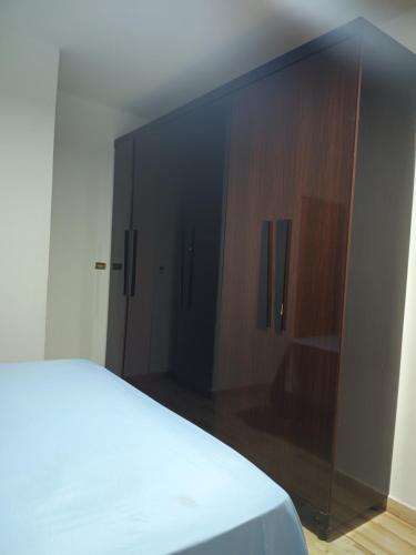 a bedroom with a bed and a wooden cabinet at Casa Dona de casa. in Ribeirão Preto