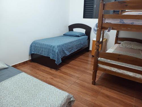 um pequeno quarto com uma cama pequena e piso em madeira em Casa Dona de casa. em Ribeirão Preto