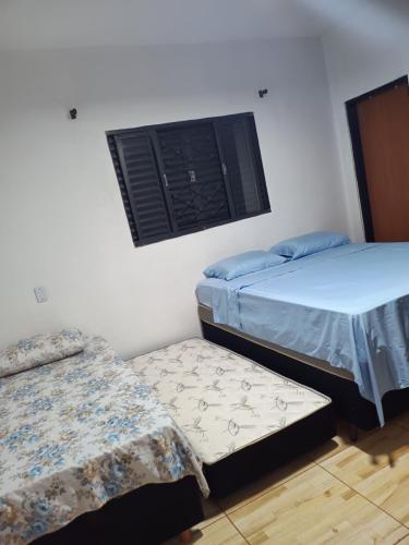 a room with two twin beds and a window at Casa Dona de casa. in Ribeirão Preto