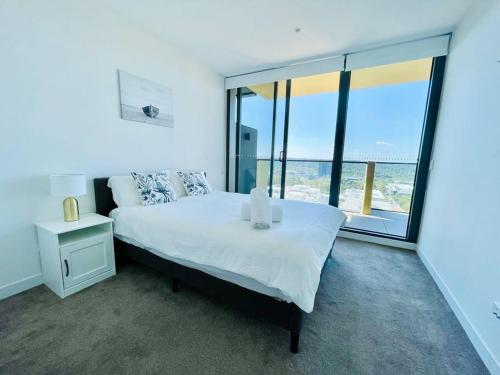 sypialnia z dużym łóżkiem i dużym oknem w obiekcie Luxury 2Beds Apt with stunning View (Parking, Gym) w mieście Sydney
