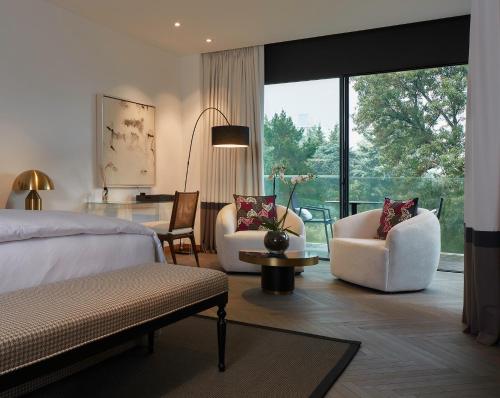 ein Schlafzimmer mit einem Bett und Stühlen sowie einem großen Fenster in der Unterkunft Casa Polanco Hotel Boutique in Mexiko-Stadt