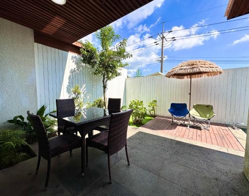 a patio with a table and chairs and an umbrella at Jeju Breeze in Seogwipo