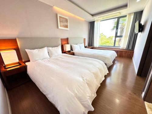 a hotel room with two beds and a window at Jeju Breeze in Seogwipo