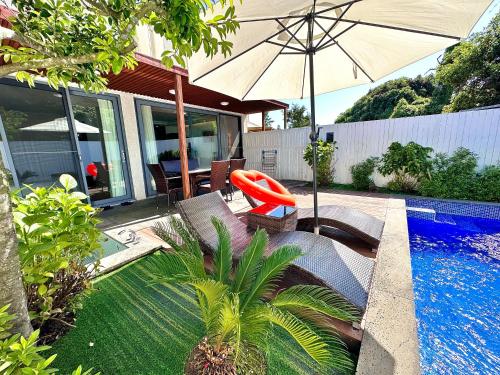 a patio with an umbrella and a swimming pool at Jeju Breeze in Seogwipo