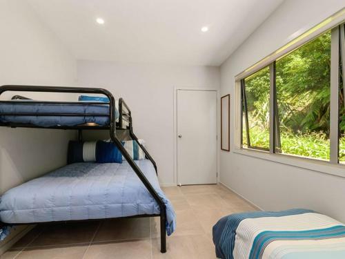 a bedroom with a bunk bed and a window at FlaxWater Lake Tarawera in Lake Tarawera
