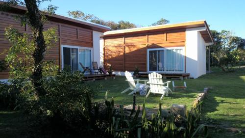a house with two white chairs in the yard at Casa da Ilha do Mel - Pousada de Charme in Ilha do Mel
