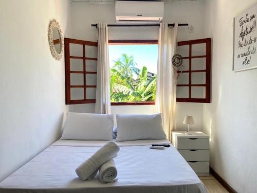 a bedroom with a white bed with a window at Casa Aconchego 5min do centro histórico e praia in Paraty