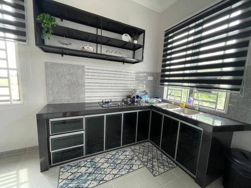 uma cozinha com um balcão preto e um lavatório em Nice bungalow with view of paddy fields em Tumpat