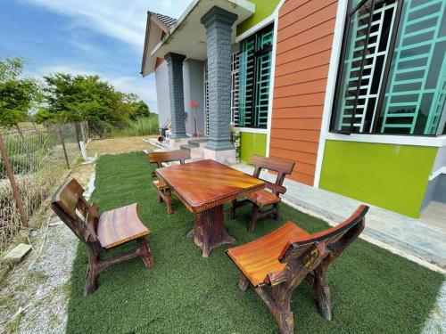a wooden table and chairs on a lawn in front of a house at Nice bungalow with view of paddy fields in Tumpat