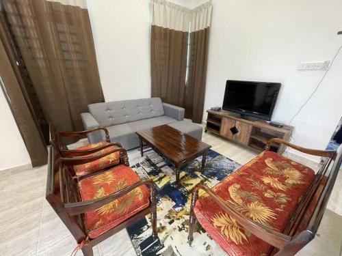 sala de estar con sofá, mesa y sillas en Nice bungalow with view of paddy fields en Tumpat