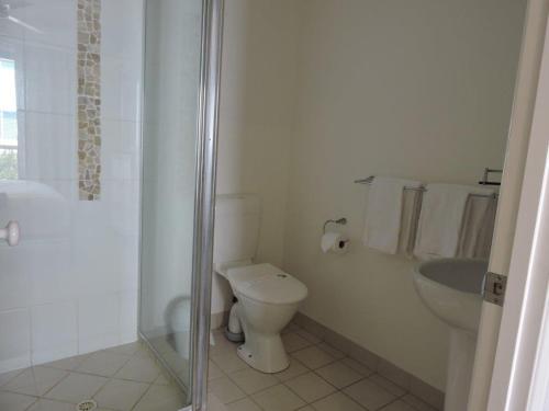 a bathroom with a toilet and a shower and a sink at Koola Beach Apartments Bargara in Bargara