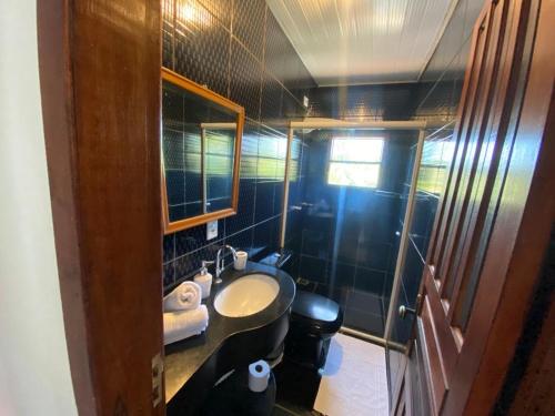 a small bathroom with a sink and a mirror at Casa Aconchego 5min do centro histórico e praia in Paraty