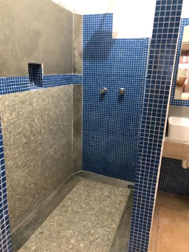 y baño con ducha de azulejos azules y lavamanos. en Casa Playa Hermosa, en Cancún