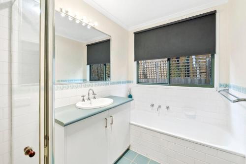 Un baño con lavabo, bañera y ducha. en Oceanswell, en Lorne