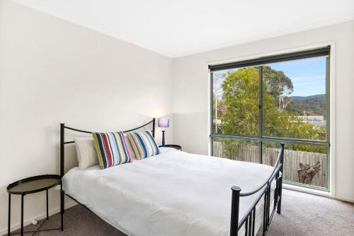 Un dormitorio con una cama y una ventana grande. en Oceanswell, en Lorne