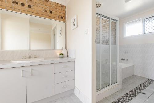 a white bathroom with a sink and a shower at Clippers 1 - Pet Friendly in Yamba