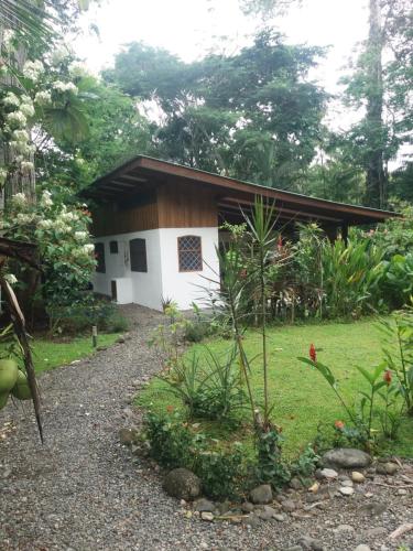 a small white building in the middle of a yard at Los Delfines Lodge in Puerto Viejo