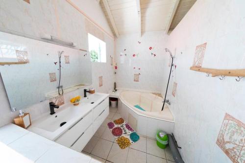 biała łazienka z wanną, umywalką i wanną w obiekcie Studio Soleil Couchant w mieście Pointe-Noire