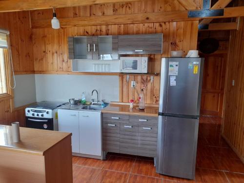 a kitchen with a stainless steel refrigerator and wooden walls at Cabaña del Vino in Santa Cruz
