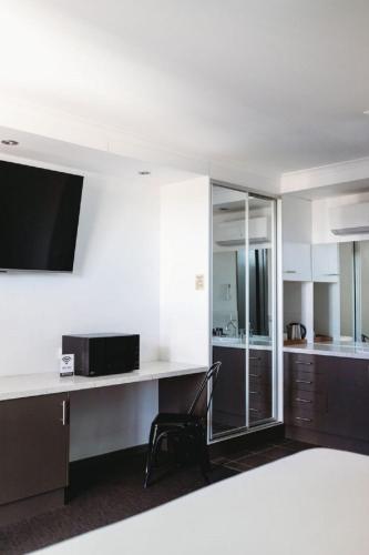 a room with a kitchen and a desk with a microwave at Echuca Nirebo Motel in Echuca