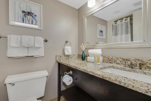 a bathroom with a sink and a toilet and a mirror at Oceanview Studio Escape With Beach Steps Away! 1828 in Myrtle Beach