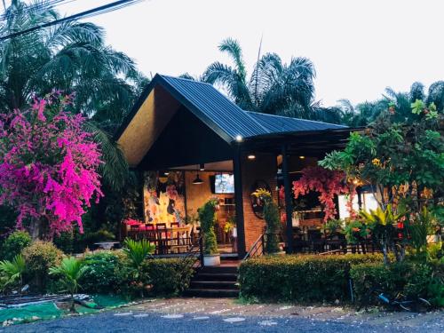 ein Haus mit einem Restaurant mit rosa Blumen und Bäumen in der Unterkunft กอบสุข รีสอร์ท2 k13 in Ban Ton Liang