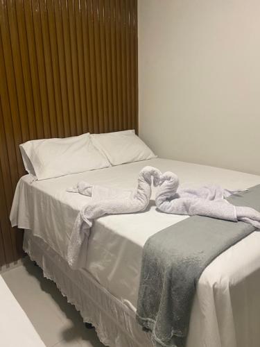 uma cama com lençóis brancos e toalhas em Origem em Mamanguape