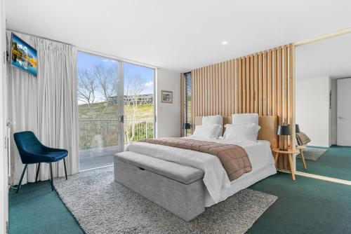a bedroom with a large bed and a large window at The Chocolate Box - Waipu Cove Holiday Home in Waipu