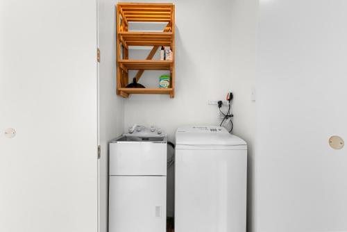 a white kitchen with two refrigerators and a shelf at The Chocolate Box - Waipu Cove Holiday Home in Waipu