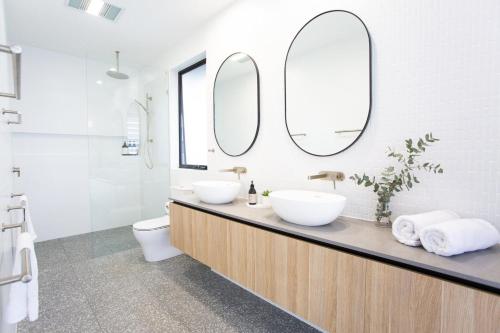 a bathroom with two sinks and two mirrors at Breeze at Salt - Wheelchair Accessible with Heated Pool in Kingscliff