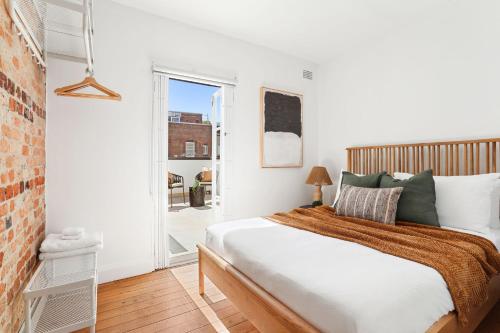 a white bedroom with a bed and a window at Stylish Darlinghurst Townhouse l 3 Bedrooms in Sydney
