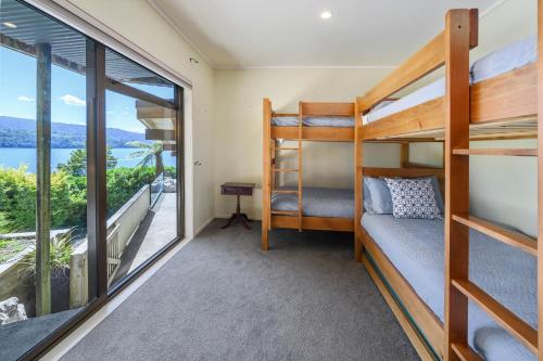 a bedroom with bunk beds and a balcony at Tironui Lake Tarawera in Lake Tarawera