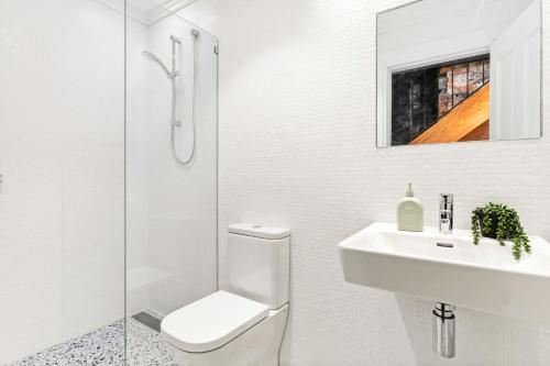 a white bathroom with a toilet and a sink at Redfern Terrace House l 2 Bedrooms & Loft in Sydney