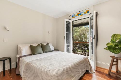 a white bedroom with a bed and a window at Redfern Terrace House l 2 Bedrooms & Loft in Sydney