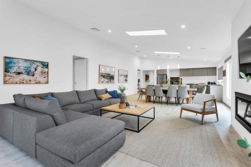 ein Wohnzimmer mit einer grauen Couch und einem Tisch in der Unterkunft Meadow by the Sea by Ready Set Stay in Rye