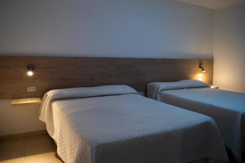2 camas en una habitación con luces en la pared en Sierras Apartamentos en Villa Santa Cruz del Lago